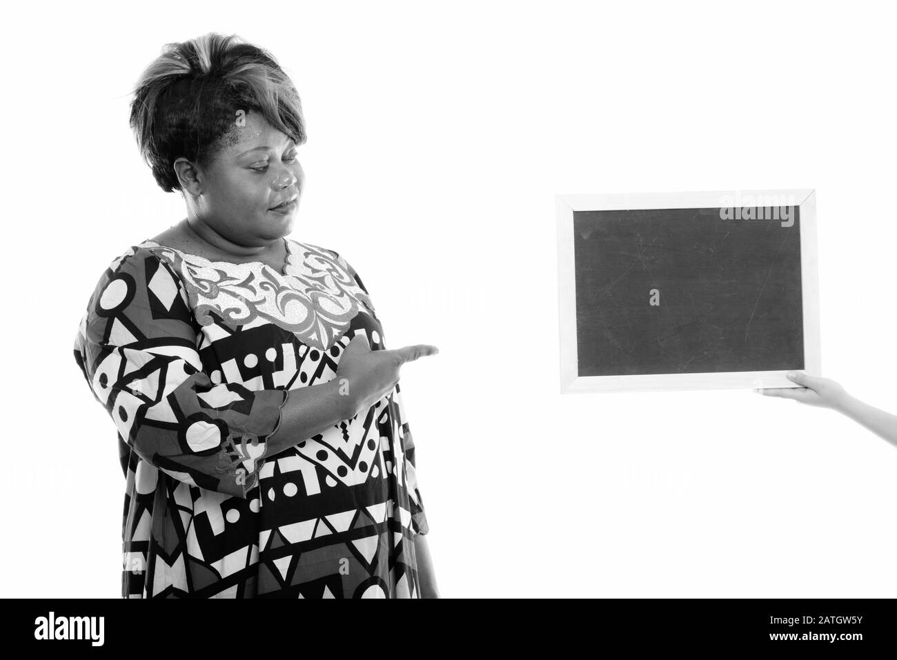 Studioaufnahme der fettschwarzen Afrikanerin, die auf eine leere Tafel blickt und zeigt Stockfoto