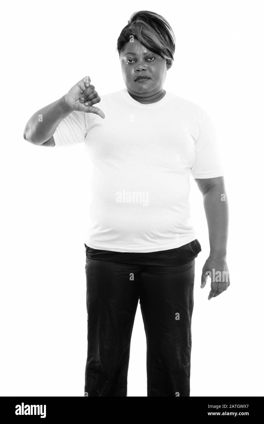Studio mit fetter schwarzer Afrikanerin, die steht und den Daumen nach unten für die Sporthalle gibt Stockfoto