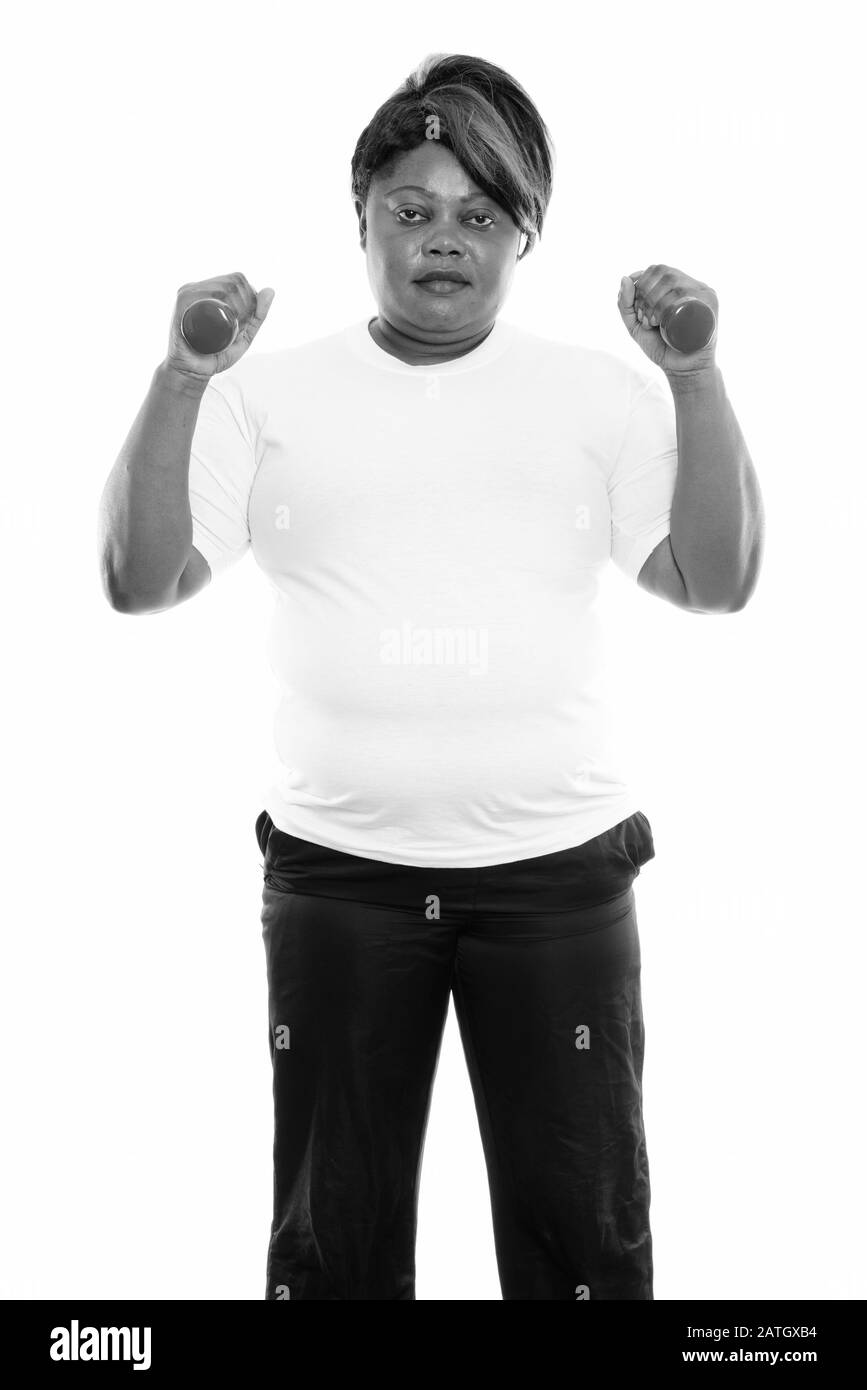 Studio Schuss von fetter schwarzer Afrikanerin steht, während sie die Hanteln für die Sporthalle bereithält Stockfoto