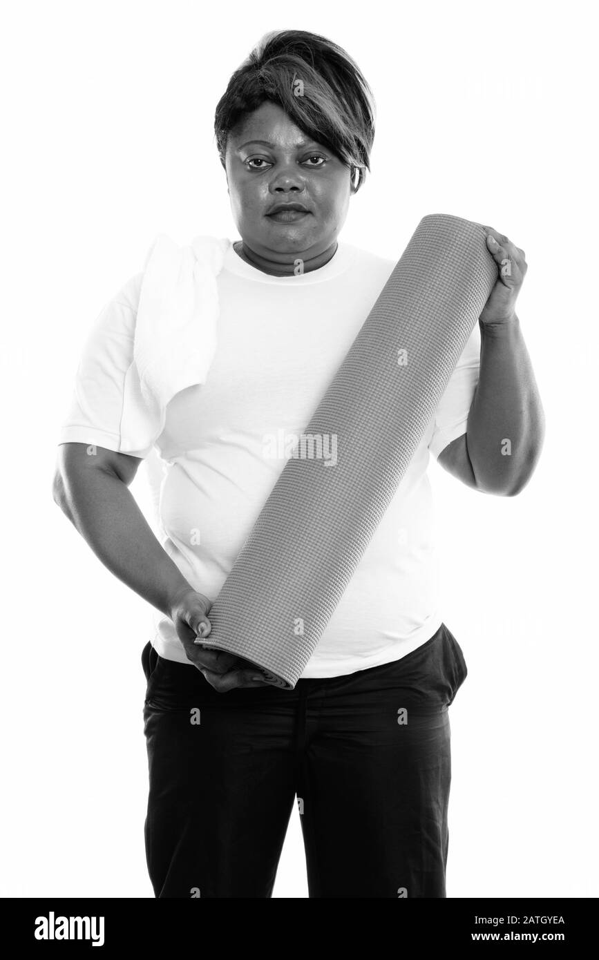 Studio-Schuss von fetter schwarzer Afrikanerin steht während der Yoga-Matte bereit für das Fitnessstudio Stockfoto