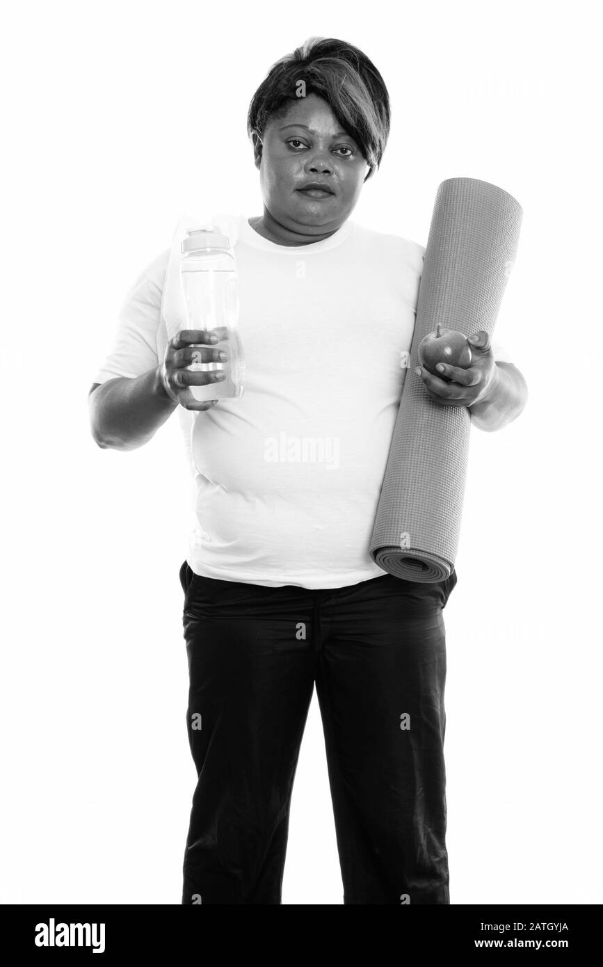 Studio-Schuss von übergewichtiger Afrikanerin mit Yogamatte und Wasserflasche bereit für den Fitnessbereich Stockfoto