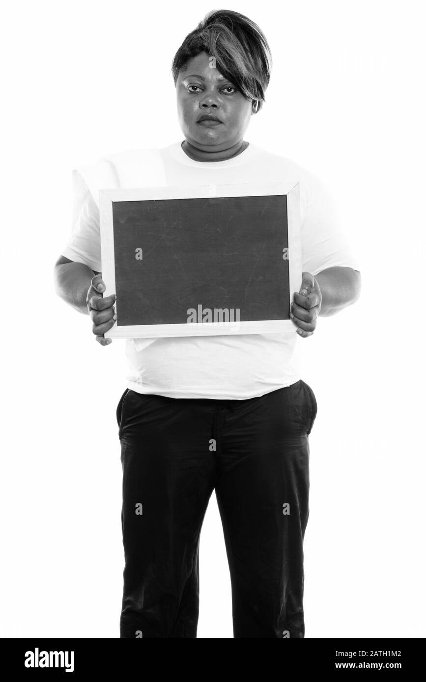 Studio-Schuss von fetter, schwarzer Afrikanerin steht, während sie eine leere Tafel für die Sporthalle bereithält Stockfoto