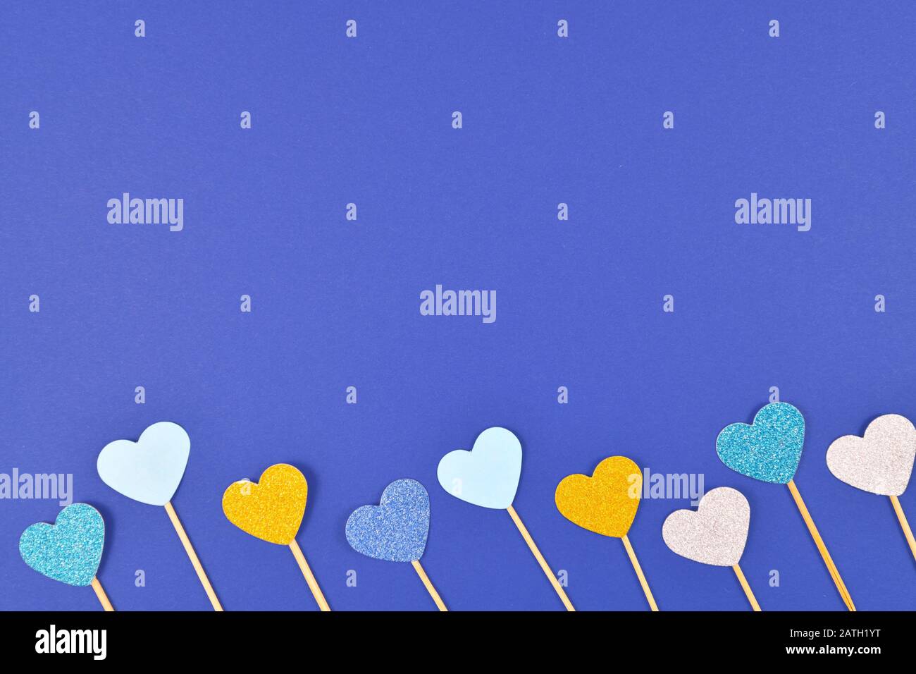 Blauer Valentinhintergrund mit glitzernden hellblauen und weißen Papierherzen unten und leerem Kopierraum oben Stockfoto