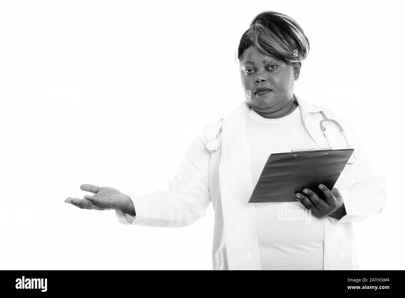 Studio Schuss von fetten schwarzen afrikanischen Frauen Doktor hält Zwischenablage, während er etwas zeigt Stockfoto