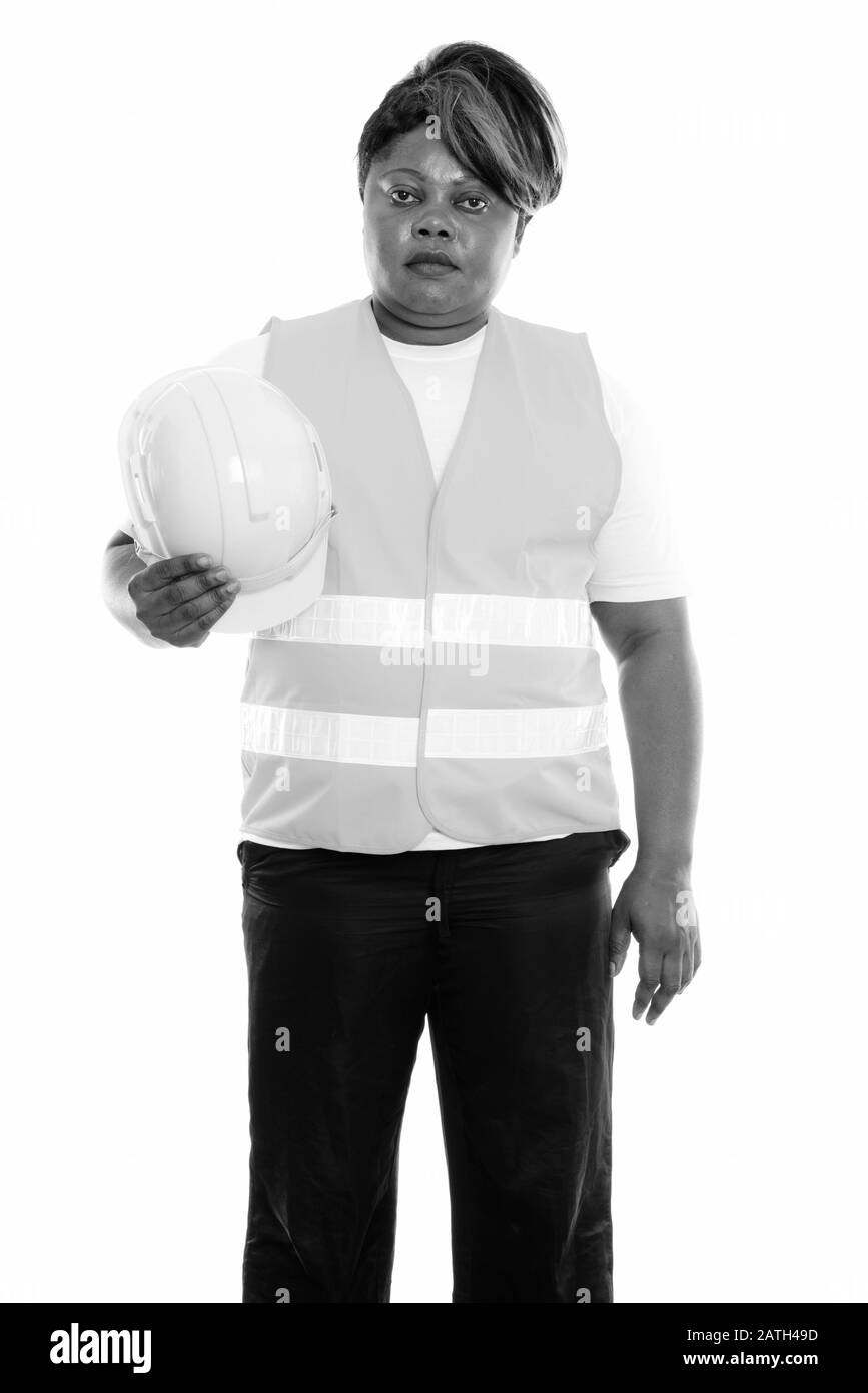 Studioaufnahme der fettschwarzen Afrikanerin, Bauarbeiterin, die steht, während sie den Hut hält Stockfoto