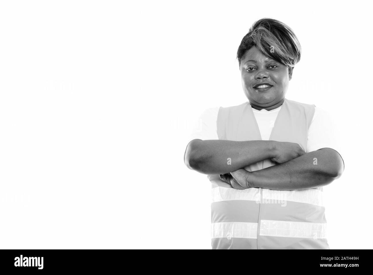 Studio Schuss von fröhlicher, fettschwarzer afrikanischer Bauarbeiterin, lächelnd mit gekreuzten Armen Stockfoto