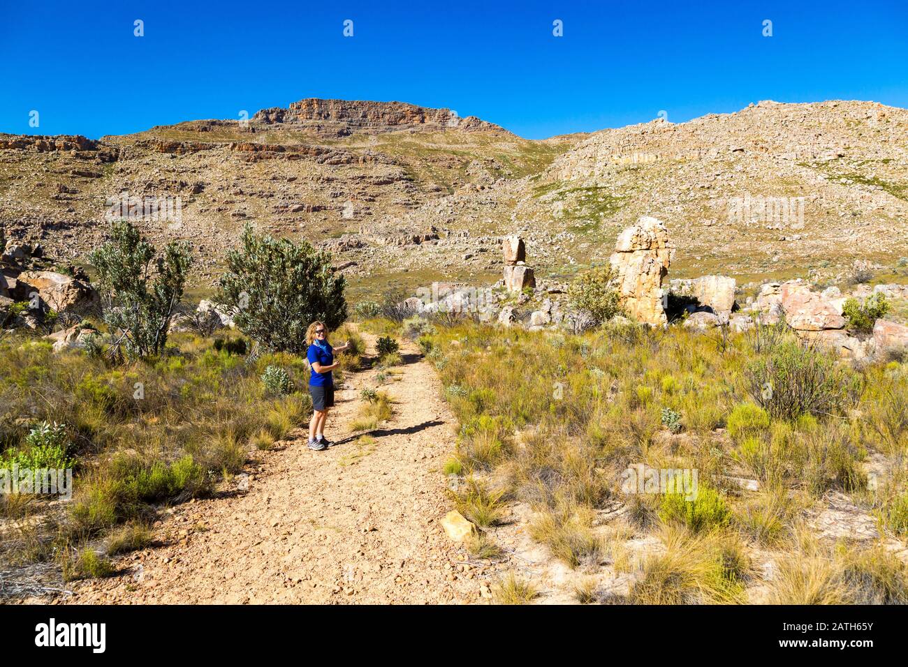 Blick auf den Wanderweg zum Malteserkreuz - ein beliebtes Wanderziel im Cederberger Gebiet (Südafrika) mit einer jungen Frau, die auf den Berg zeigt Stockfoto