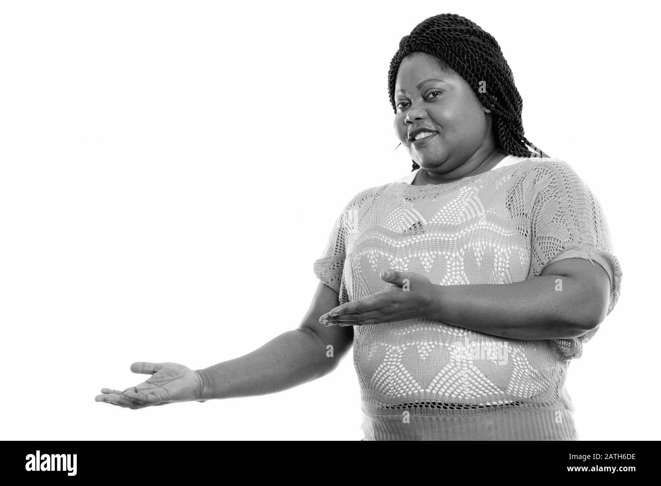 Studioaufnahme einer fröhlichen, fettschwarzen Afrikanerin, die lächelt, während sie etwas zeigt Stockfoto