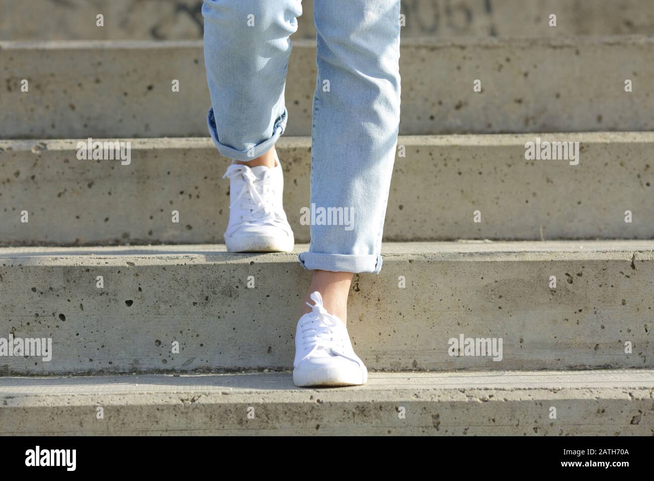 Vorderansicht Nahaufnahme der Beine einer Frau, die Turnschuhe trägt, die Treppen hinuntergehen Stockfoto