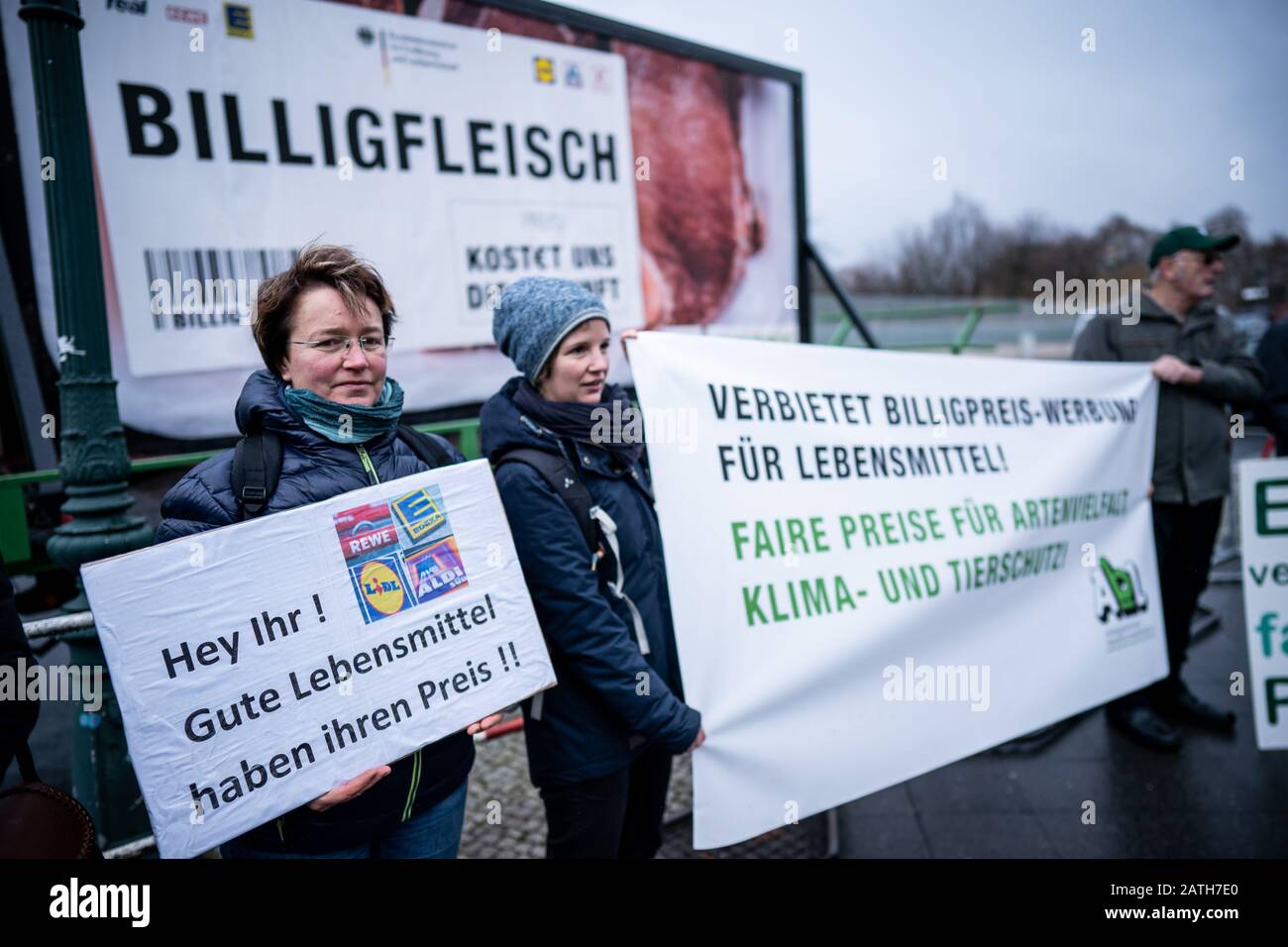 03. Februar 2020, Berlin: Aktivisten der "Arbeitsgemeinschaft bäuerlicher Landwirtschaft" und der Umweltschutzorganisation Greenpeace stehen vor dem Bundeskanzleramt mit einem Protestschild, das "Billiges Fleisch kostet uns die Zukunft" (l-r) und "Verbotene billige Werbung für Lebensmittel" sagt. Im Streit um die Lebensmittelpreise in Supermärkten diskutieren Vertreter des Einzelhandels und der Lebensmittelindustrie bei einem Spitzentreffen mit Kanzlerin Merkel, Landwirtschaftsminister Klöckner und Wirtschaftsminister Altmaier über Lösungen. Foto: Michael Kappeler/d Stockfoto