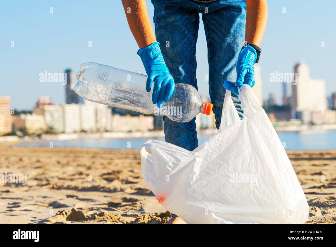 Sauberer Strand aus Kunststoff. Freiwillige Hände holen Plastikflasche Müll vom Strand und in Plastiktüte zum Recycling Stockfoto