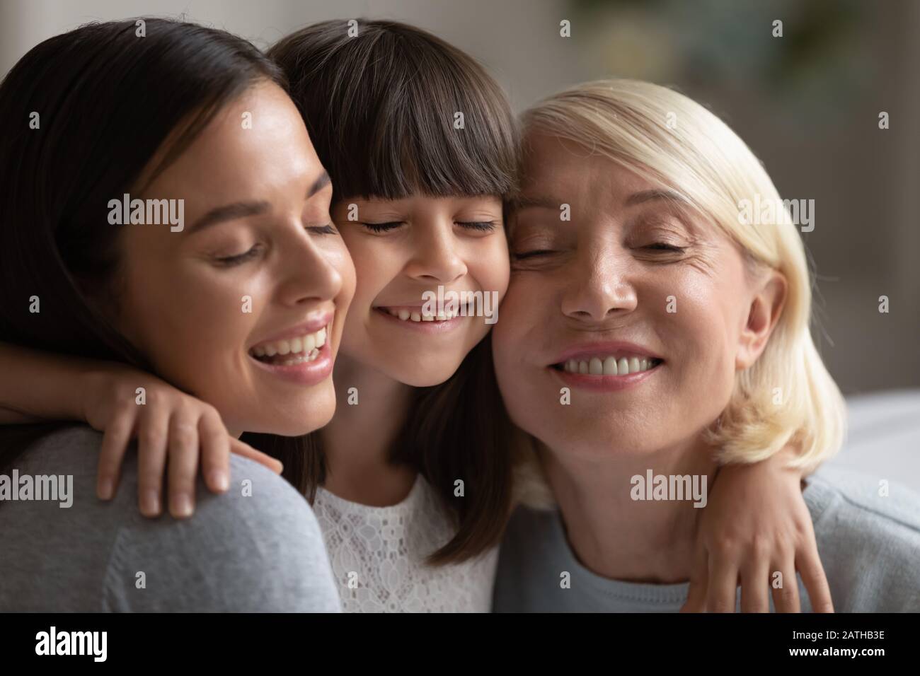 Lächelnde drei Generationen von Frauen umarmen und kuscheln Stockfoto