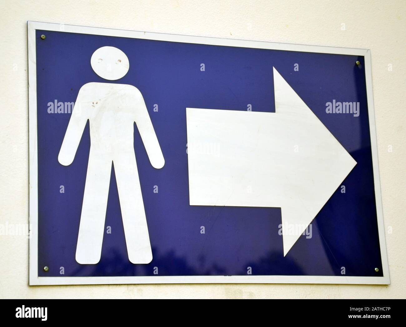 Ein blaues Schild mit dem Symbol für einen Mann und einem Pfeil zeigt den Weg zur männertoilette oder Toilette Stockfoto