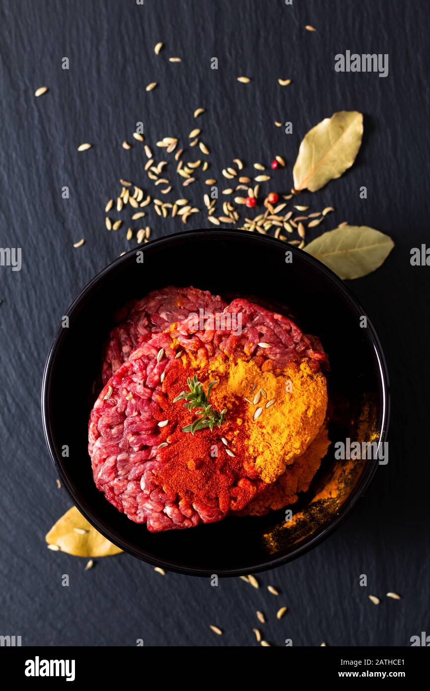 Lebensmittelzubereitungszutaten Konzept Bio roh Hackfleisch oder gemahlenes Rindfleisch mit Gewürzen für orientalische Lebensmittel Keema Curry auf schwarzem Schieferstein mit c Stockfoto