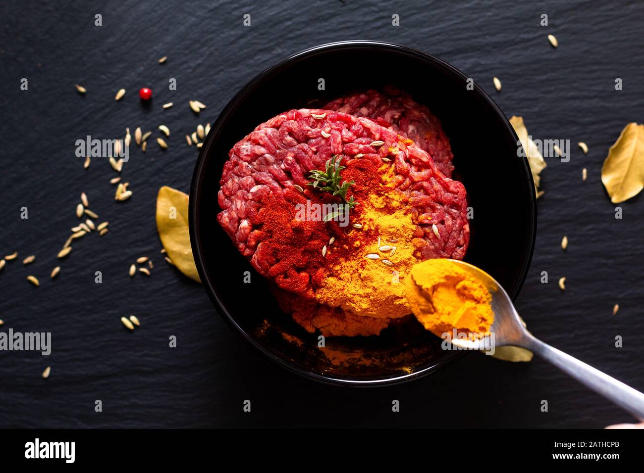 Lebensmittelzubereitungszutaten Konzept Bio roh Hackfleisch oder gemahlenes Rindfleisch mit Gewürzen für orientalische Lebensmittel Keema Curry auf schwarzem Schieferstein mit c Stockfoto