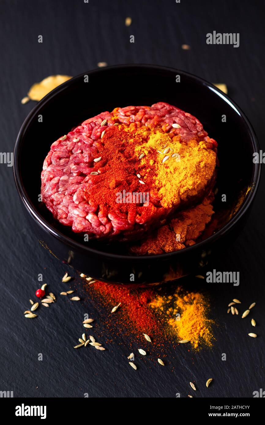 Lebensmittelzubereitungszutaten Konzept Bio roh Hackfleisch oder gemahlenes Rindfleisch mit Gewürzen für orientalische Lebensmittel Keema Curry auf schwarzem Schieferstein mit c Stockfoto