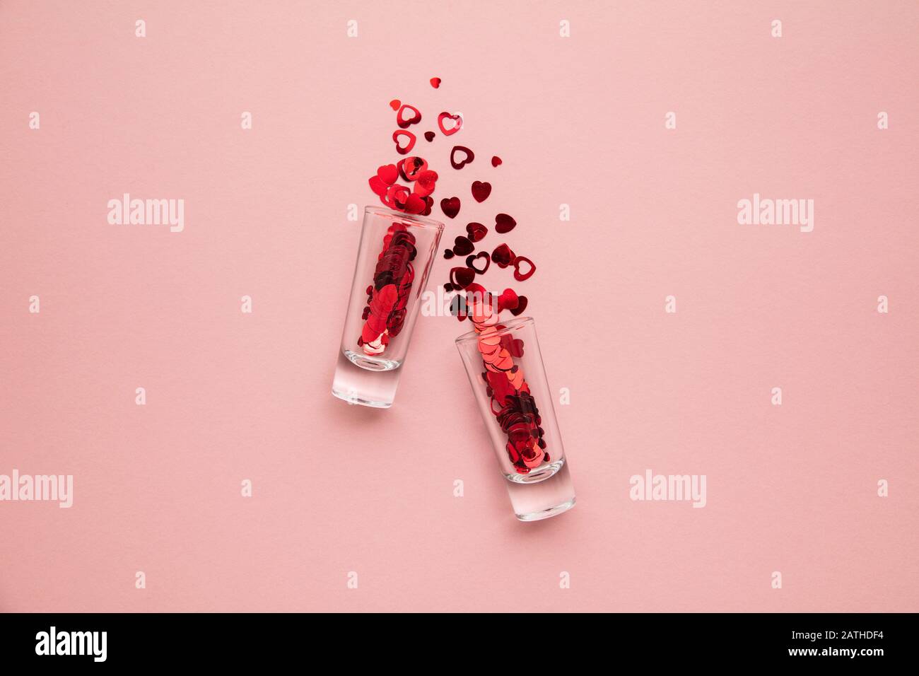 Valentinstagsaufnahmen. Glas mit Herzkonfetti auf pastellrosa Hintergrund Stockfoto