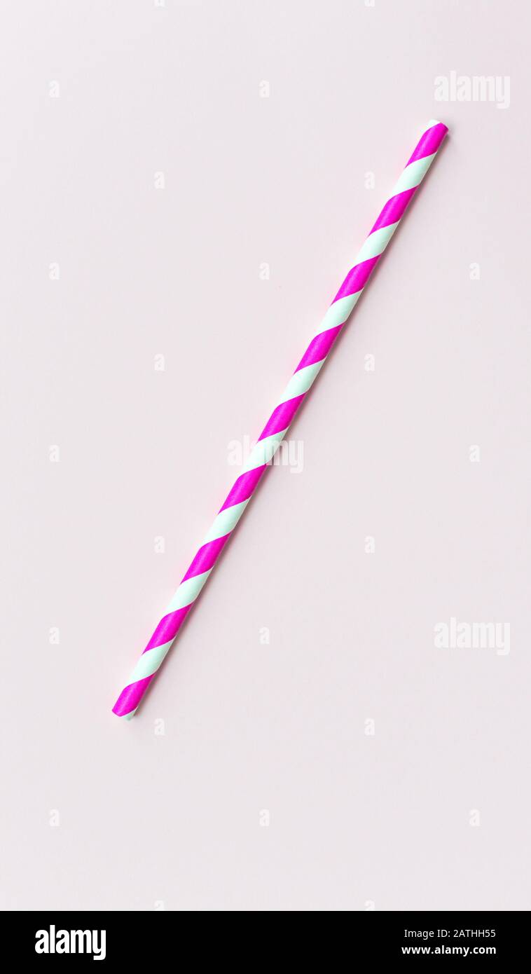 Einzelnes Papierstroh in rosafarbenen Streifen auf einem rosafarbenen Hintergrund Stockfoto