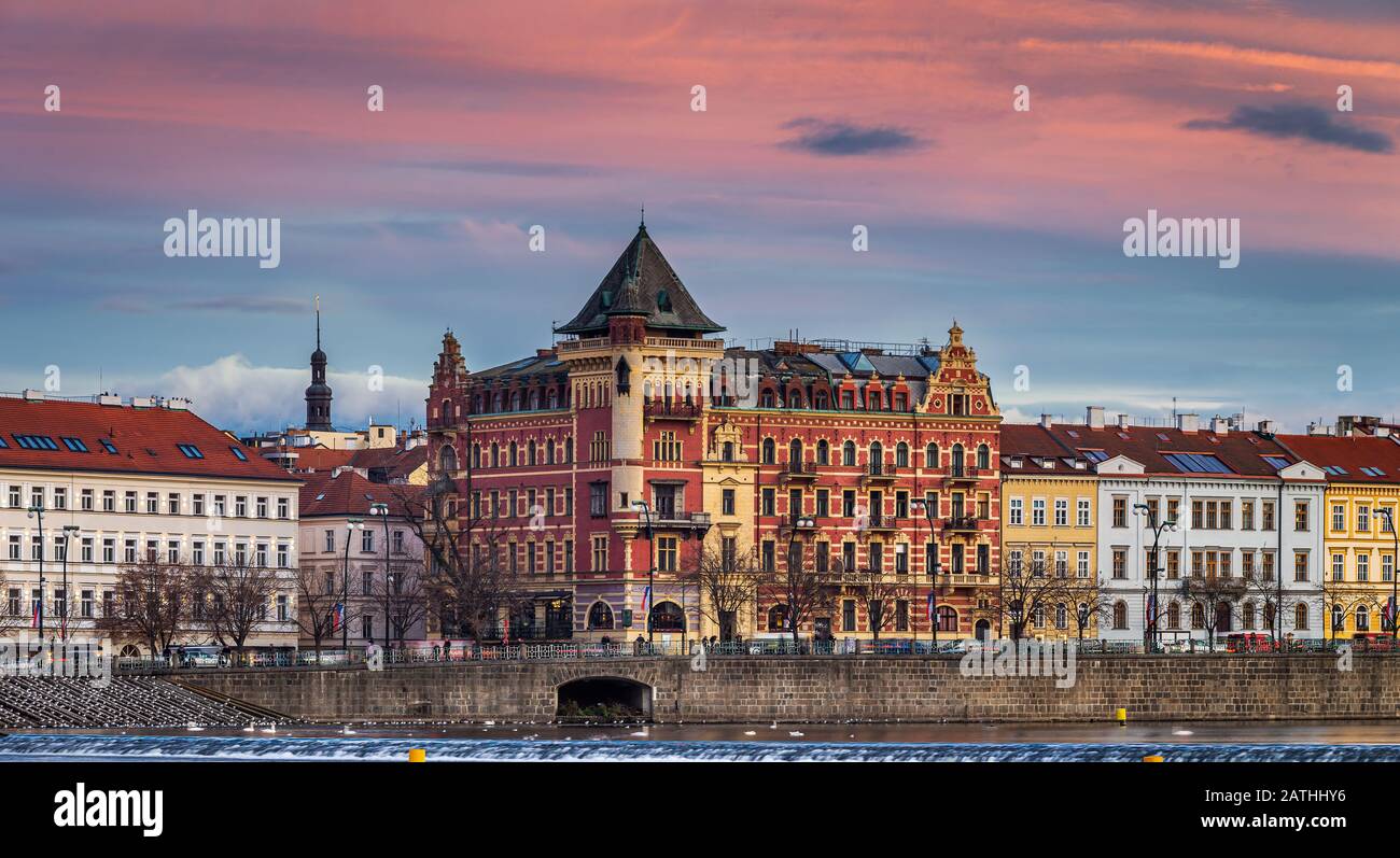 Prag, Tschechien - Panoramablick auf den Prager Fluss im Winter mit traditionellen Gebäuden, Hotels und wunderschönem violettem Himmel bei Sonneneingängen Stockfoto