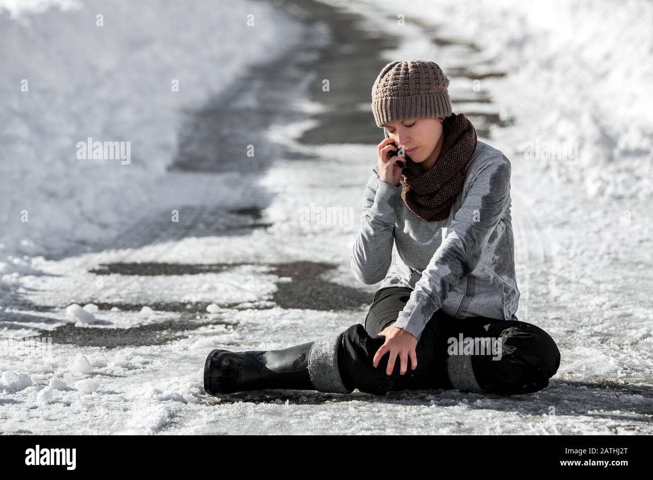 Frau rutschte auf der Winterstraße mit schwarzem Eis, Notruf um Hilfe, Unfall und Verletzung, Copyspace Stockfoto