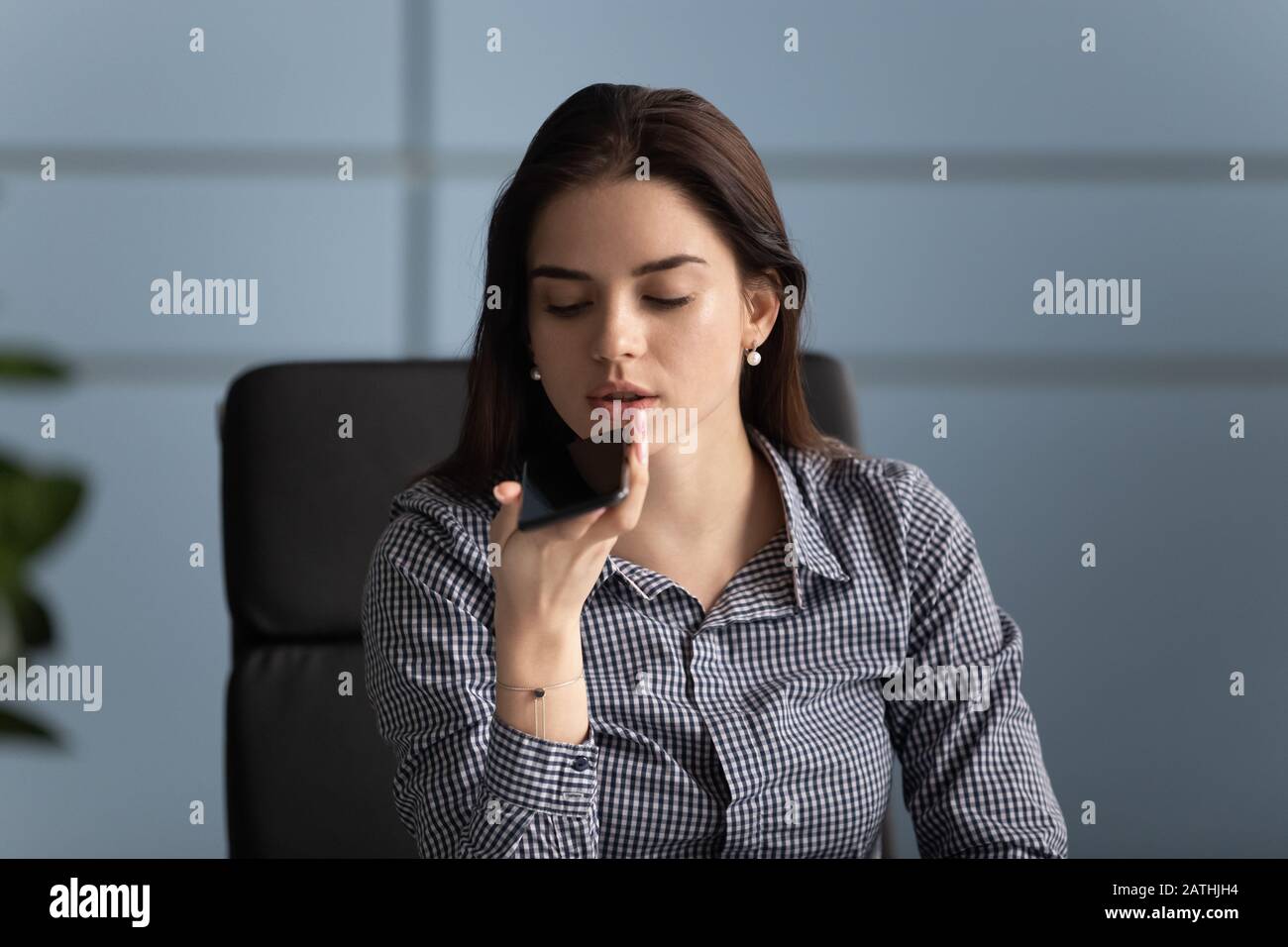 Tausendjährige Arbeiterinnen, die ein Smartphone zur Aufzeichnung von Sprachnachrichten halten Stockfoto