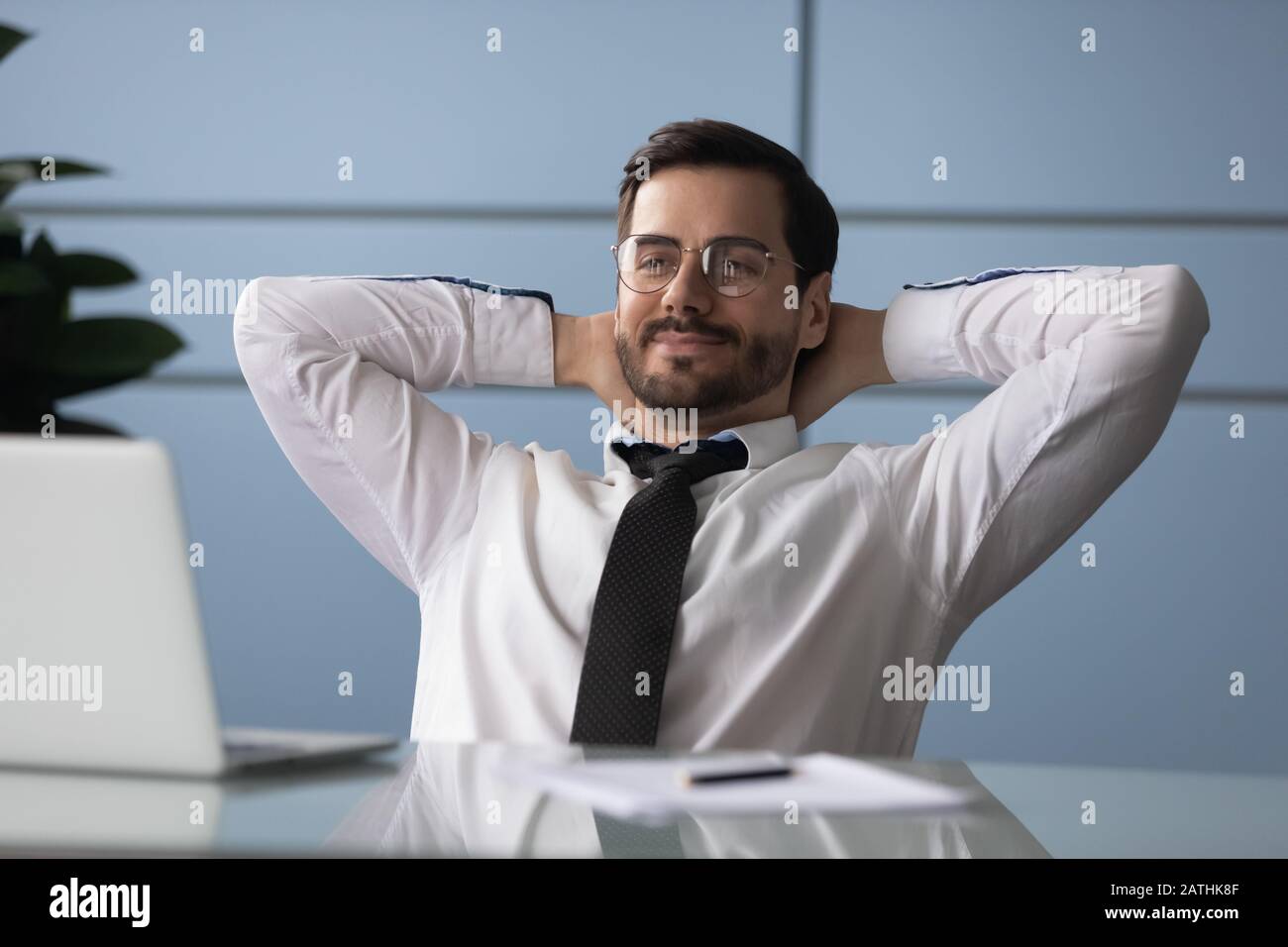 Der Geschäftsmann hat die Hände hinter den Kopf gelegt und genießt eine Pause am Arbeitsplatz Stockfoto