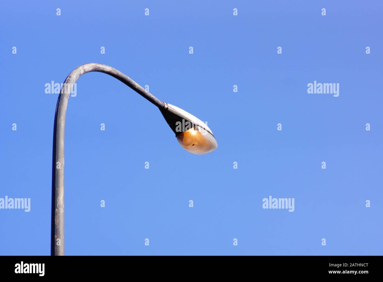 Straßenleuchte an gebogenem Pfosten, der tagsüber läuft Stockfoto
