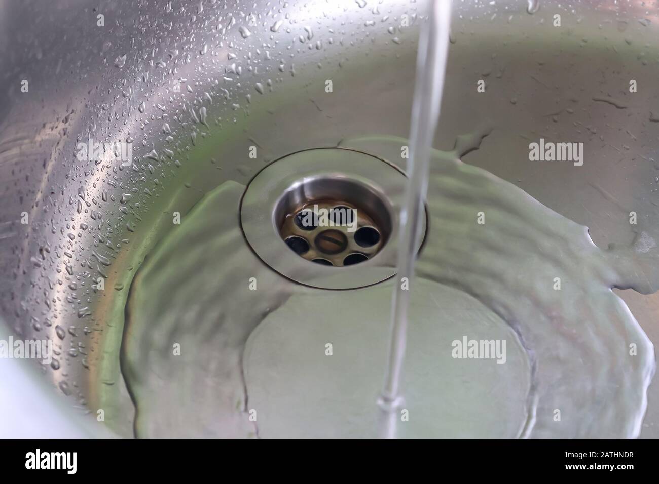 Fließendes Wasser aus einem Wasserhahn in einem metallischen Küchenwaschbecken Stockfoto