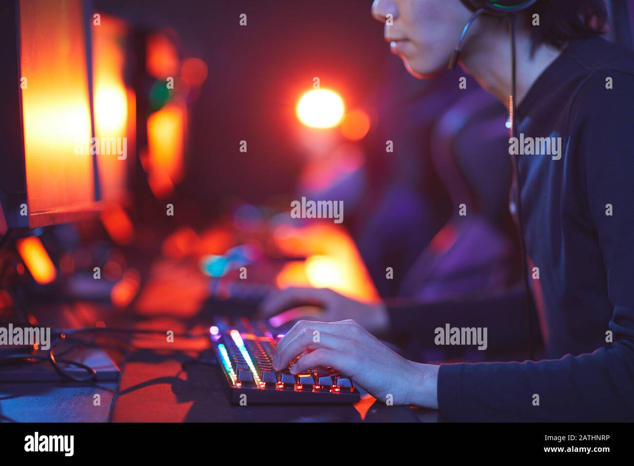 Nahansicht des jungen Asiaten, der Videospiele im dunklen Raum spielt, Fokus auf männliche Hände auf hell beleuchtete Tastatur, Kopierraum Stockfoto