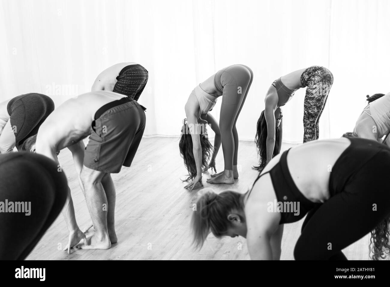 Gruppe von jungen sportlich attraktive Leute im Yoga Studio, Yoga Unterricht mit Kursleiter, gemeinsam vorwärts Band bein Streching darstellen Stockfoto