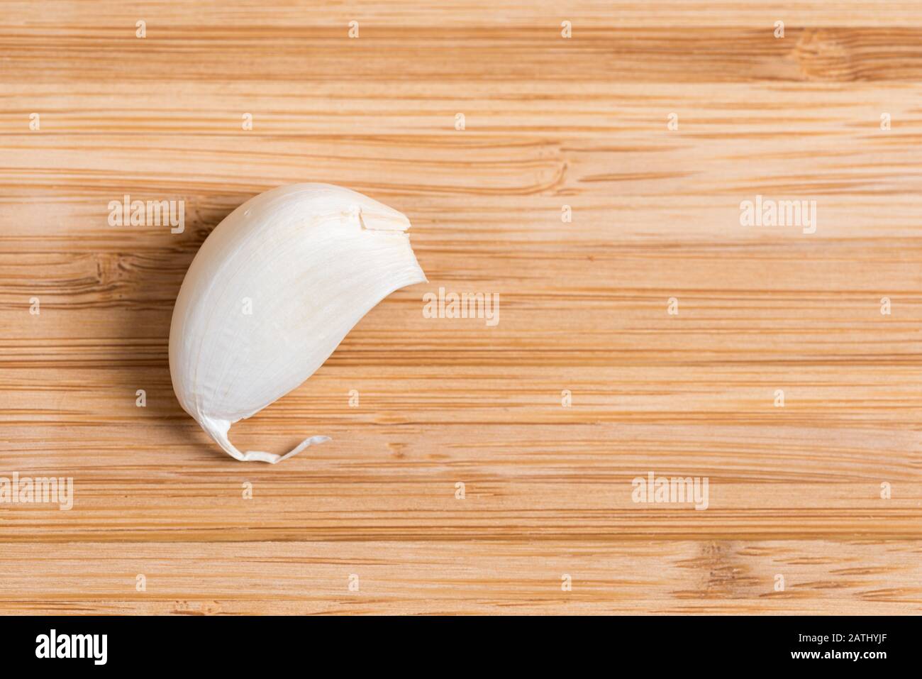 Draufsicht auf eine einzelne Knoblauchzehe, die auf einem Holzküchentisch liegt. Stockfoto