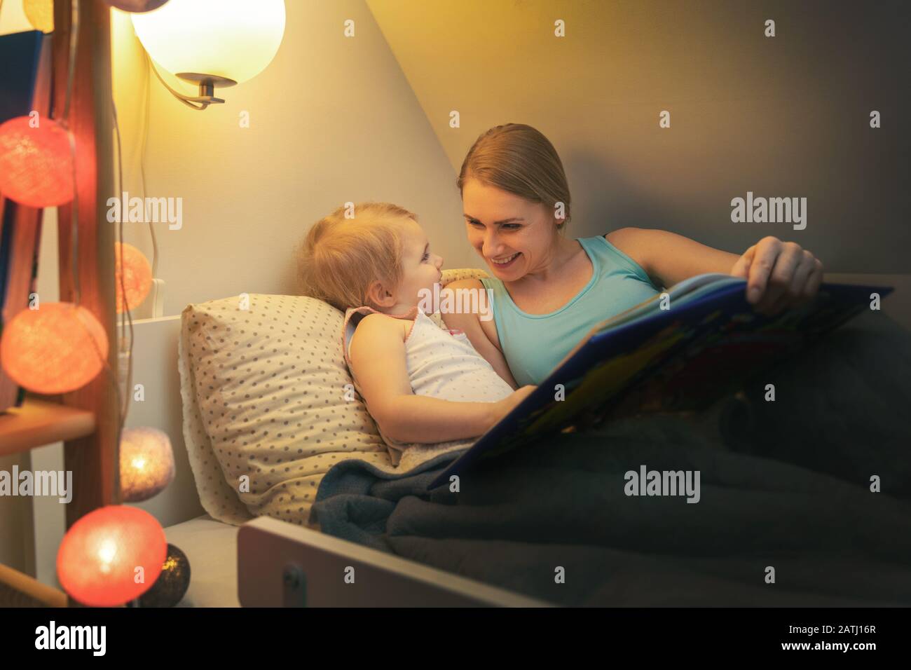 Mutter liest ihrem Kind am Abend Feenschwanz, bevor sie zuhause schläft Stockfoto