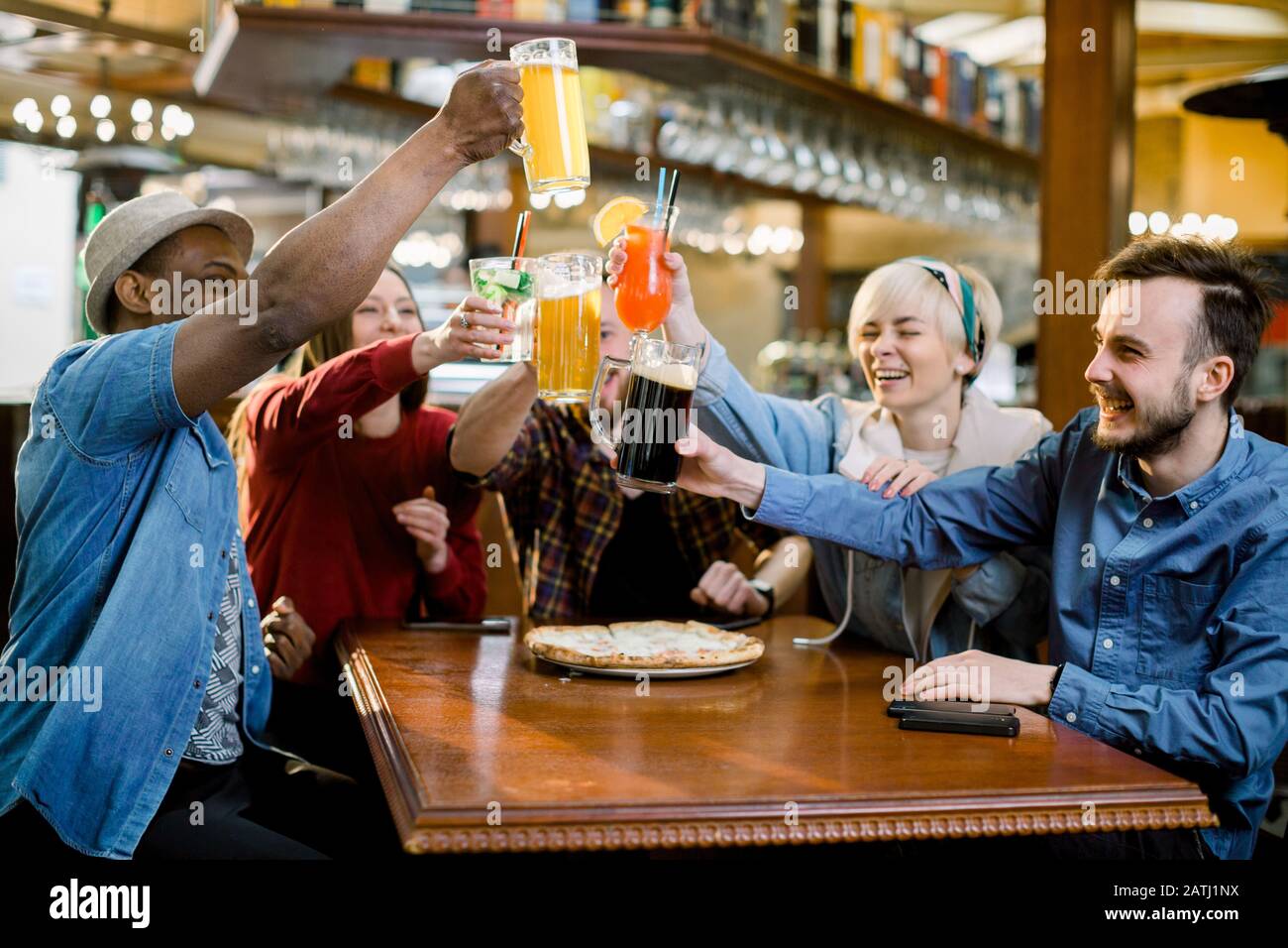 Aufgeregt diverse Freunde Fußballfans feiern Sieg Torpunktzahl Online-Spiel im fernsehen im Café, das das Siegerteam beim Bieressen unterstützt Stockfoto