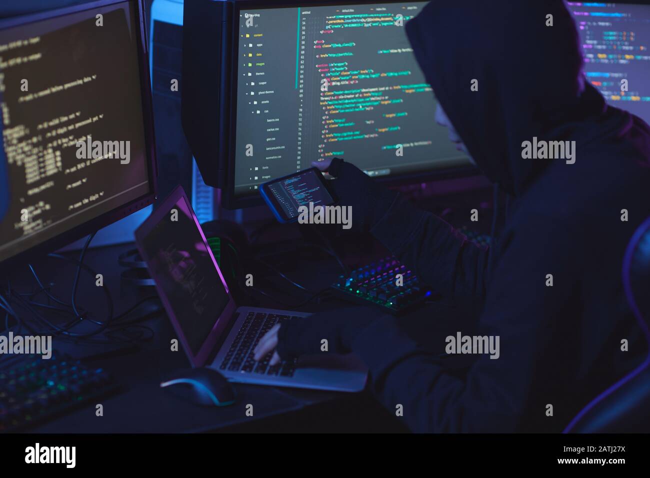 Rückansicht bei nicht erkennbarem Cyber-Security-Hacker, der Kapuze trägt, während er an der Programmierung in dunklen Räumen arbeitet, Kopierbereich Stockfoto