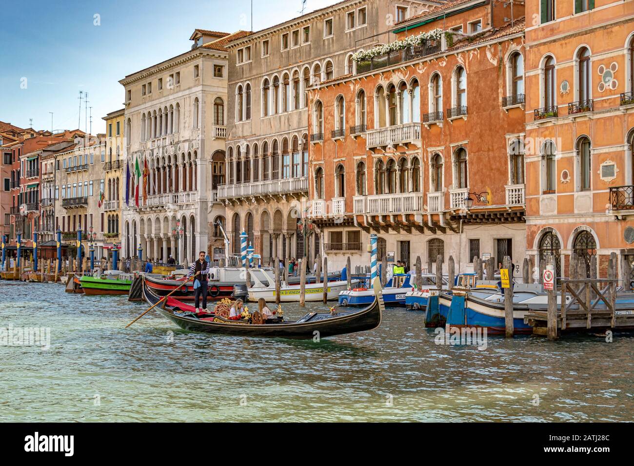 Ein Gondolier lenkt seine Gondel mit zwei Mädchen, die eine Gondelfahrt auf dem Canal Grande in Venedig, Italien, machen Stockfoto