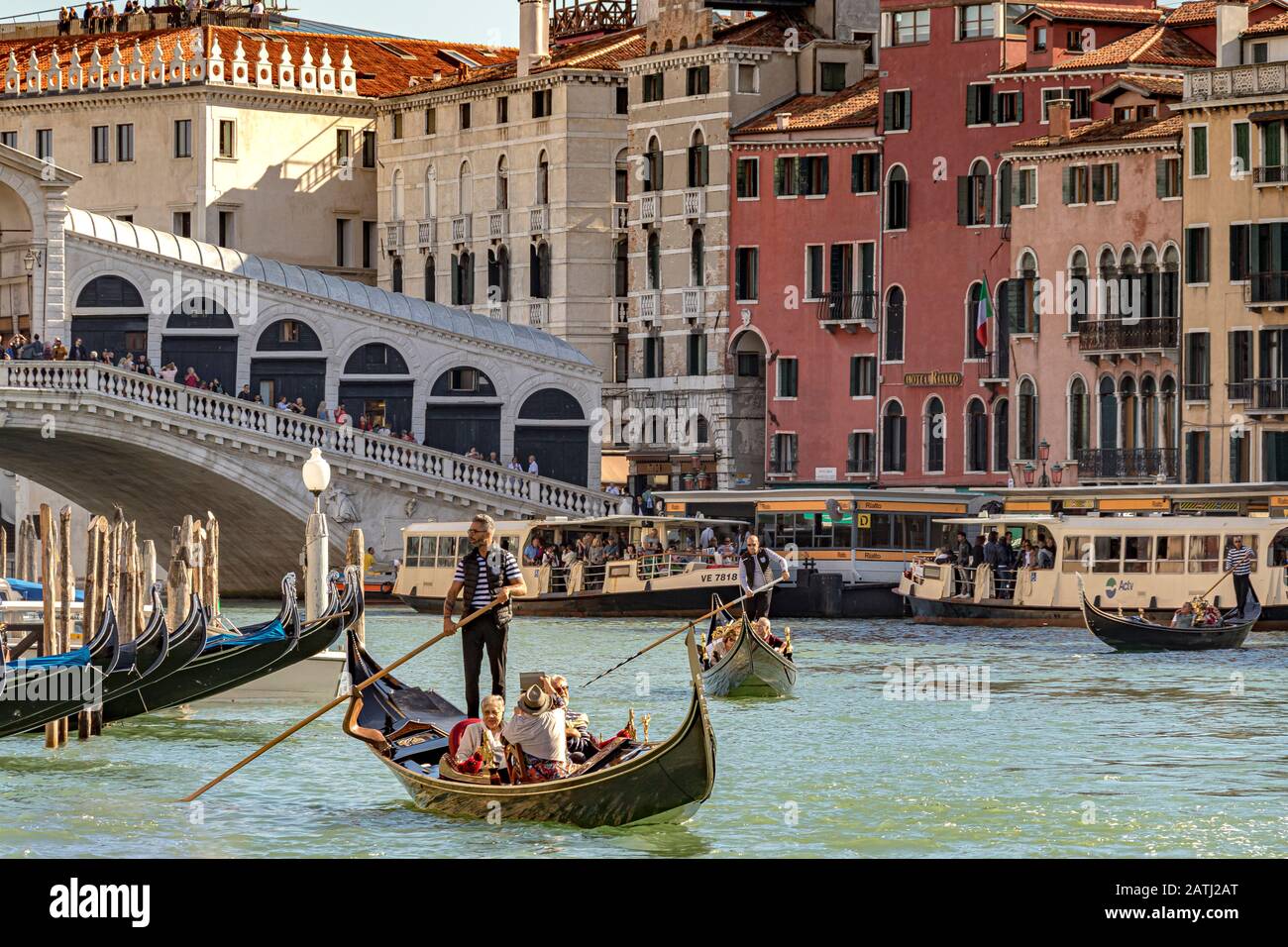 Ein Gondolier, der seine Gondel lenkt und Touristen entlang Des Canal Grande nahe Der Rialto-Brücke, Venedig, Italien, führt Stockfoto