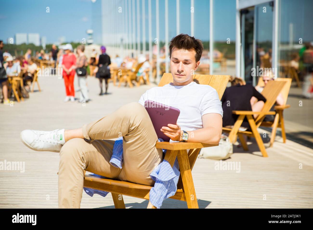 Neue Zentralbibliothek Helsinki Oodi Exterieur. Moderne nördliche Architektur. Loungebereich im oberen Stock. Menschen entspannen, Sonne genießen Stockfoto