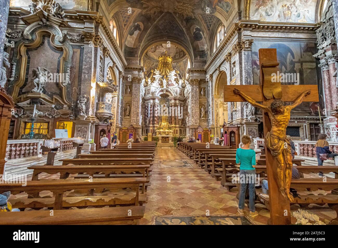 Eine Frau steht in der Nähe eines Kruzifixes im Inneren der Kirche Santa Maria di Nazareth, Venedig, Italien Stockfoto
