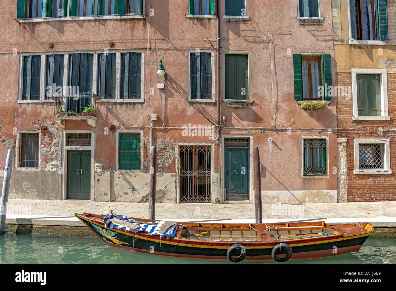 Ein leeres Holzboot, das zu Holz-Anlegepfählen vor einer Reihe von Häusern am Kanal Rio de la Caziola in Venedig, Italien, vermocht ist Stockfoto