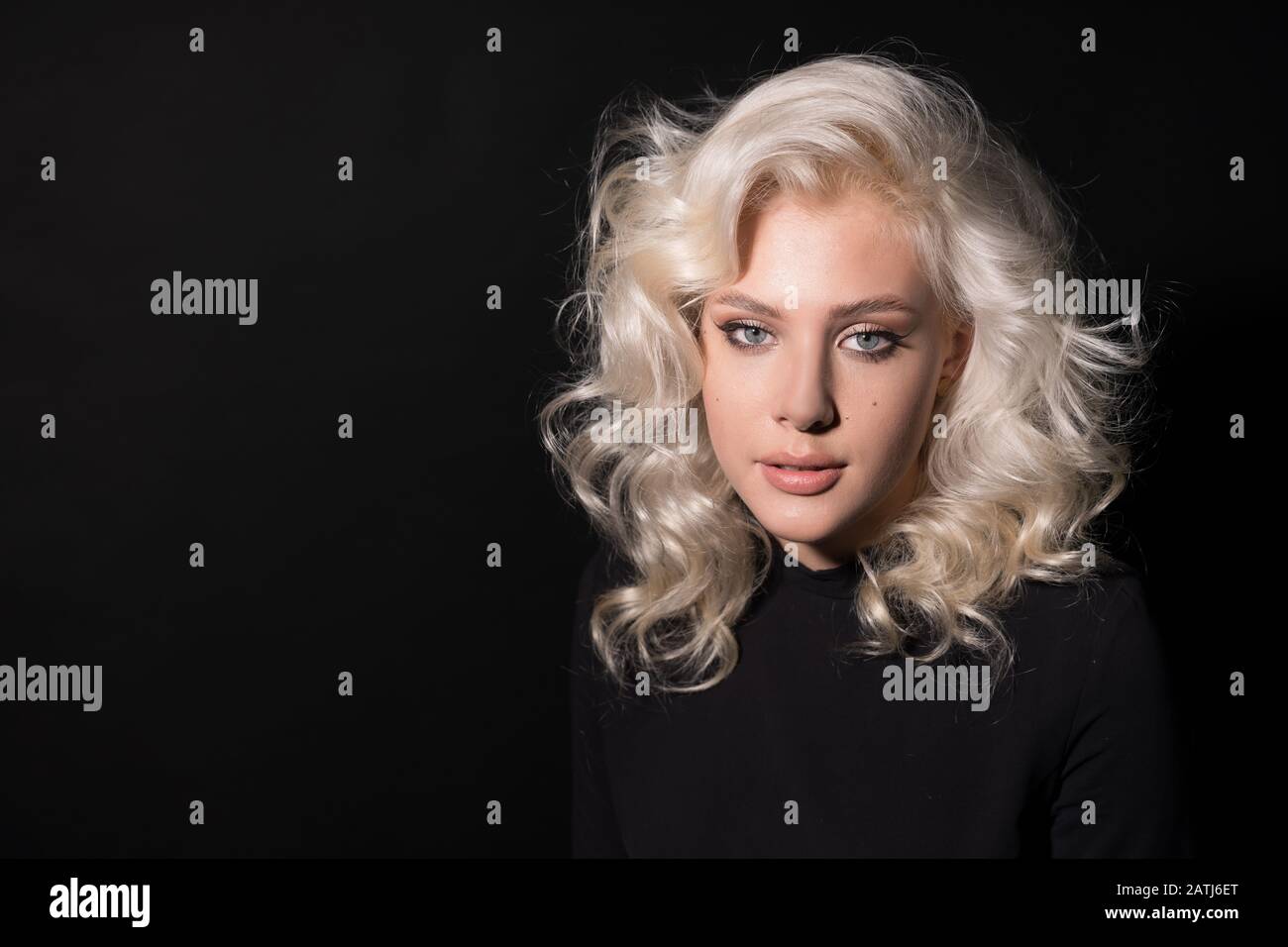 Vorderansicht des schönen blonden Mädchens isoliert auf schwarzem Hintergrund. Stockfoto