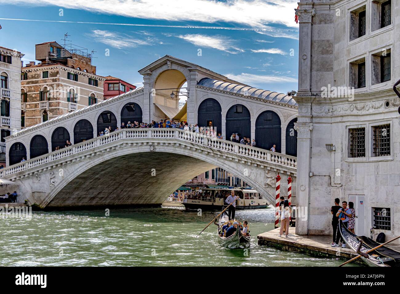 Eine Gondel macht es auf dem Weg entlang Des Canal Grande, der von einer Menschenmenge auf Der Rialto-Brücke, Venedig, Italien, beobachtet wird Stockfoto