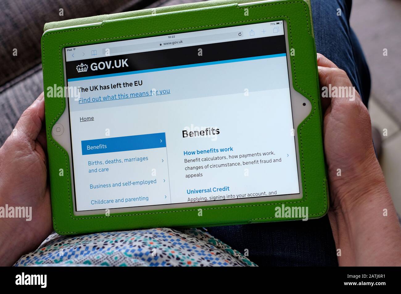 Person, die den ipad Tablet-Computer mit der Homepage gov.uk Benefits hält Stockfoto