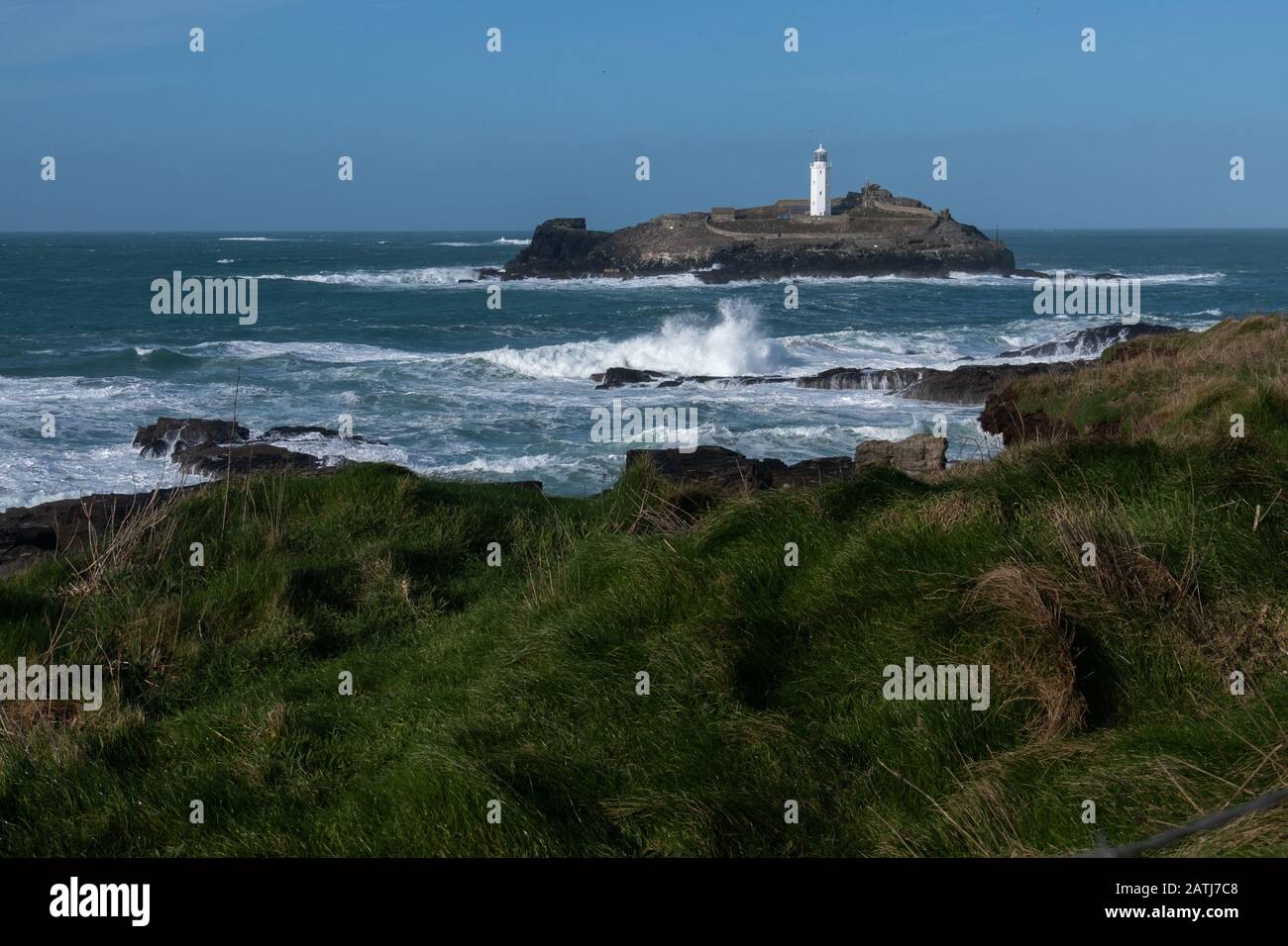 Mächtige windgetriebene Wellen, die die Felsen und die Küstenlinie rund um den Leuchtturm von Godrevy durchschlagen. Schön, aber gefährlich. Isoliert und einsam. Stockfoto