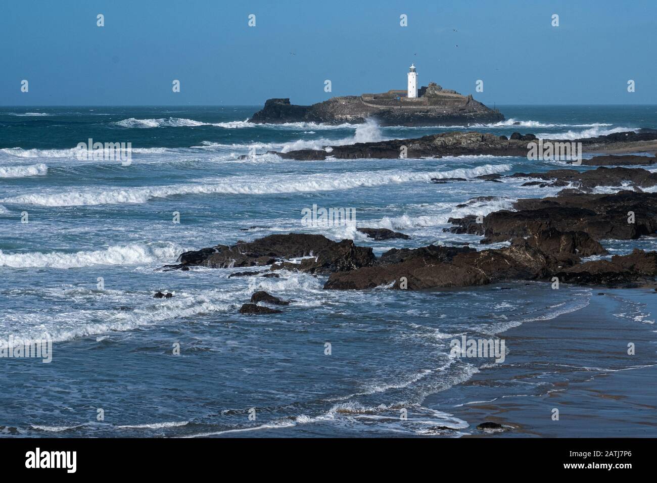 Mächtige windgetriebene Wellen, die die Felsen und die Küstenlinie rund um den Leuchtturm von Godrevy durchschlagen. Schön, aber gefährlich. Isoliert und einsam. Stockfoto