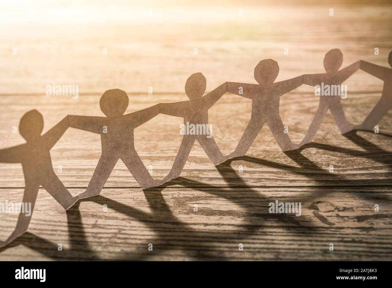 Team von Mitarbeitern der Papierkette. Menschenkette mit Licht und Schatten. Stockfoto