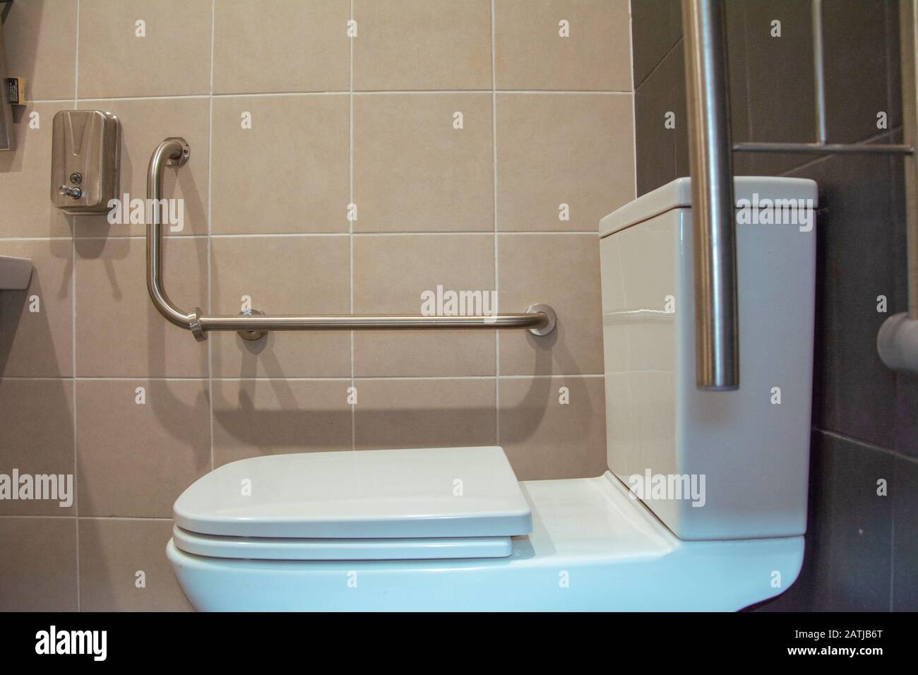 Behindertengerechte toilette mit weißen und grauen Fliesen Stockfoto