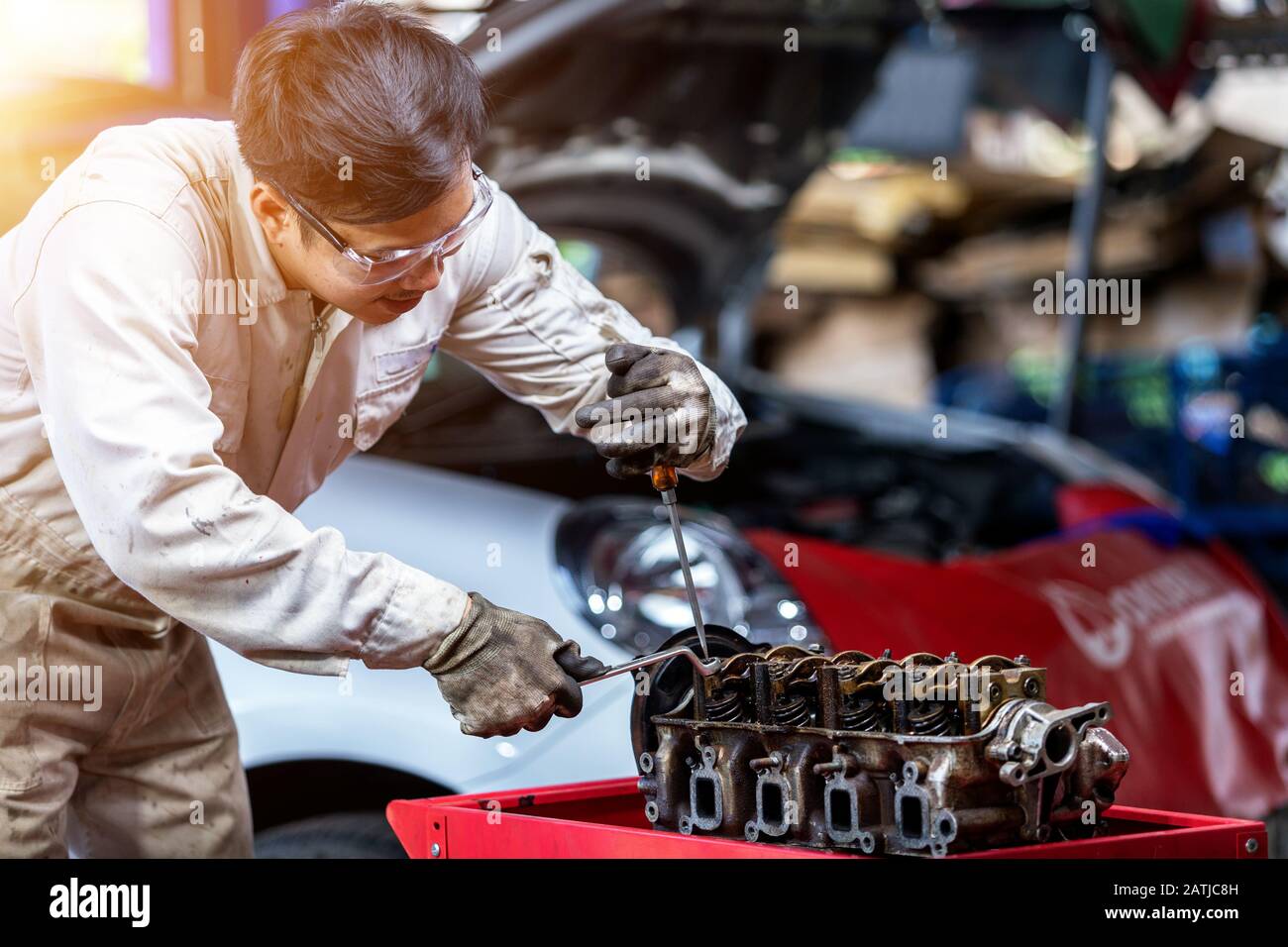 Fahrzeugtechniker, der demonstriert, wie man in der Werkstatt ein Motorventil einstellt Stockfoto