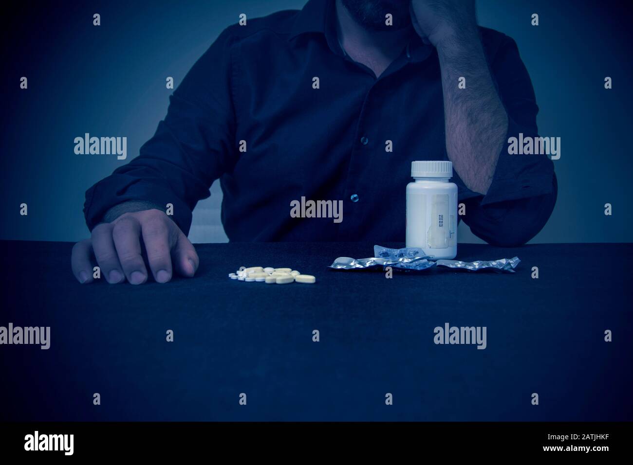 Depressiver Mann denkt, Pillen zu trinken, während er vor dem Schreibtisch steht Stockfoto Depressiver Mann denkt, Pillen zu trinken, während er vor dem Schreibtisch steht Stockfoto