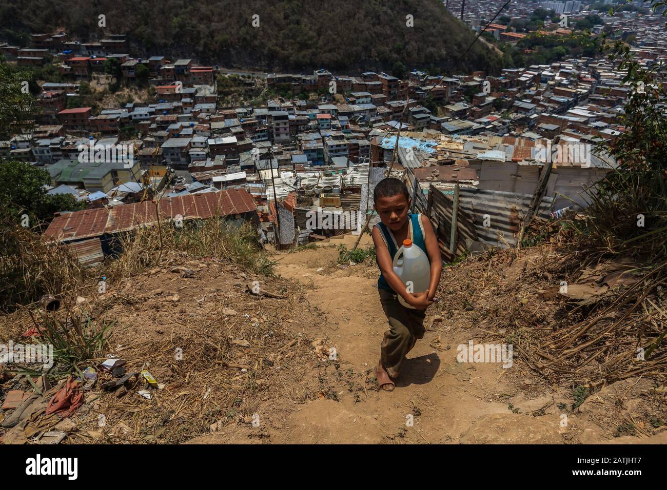 Ein Kind führt eine WasserDose zu seinem Haus, um dann mehrere Tage ohne Wasser in den Hochgemeinden der Stadtviertel Caracas zu verbringen. Stockfoto