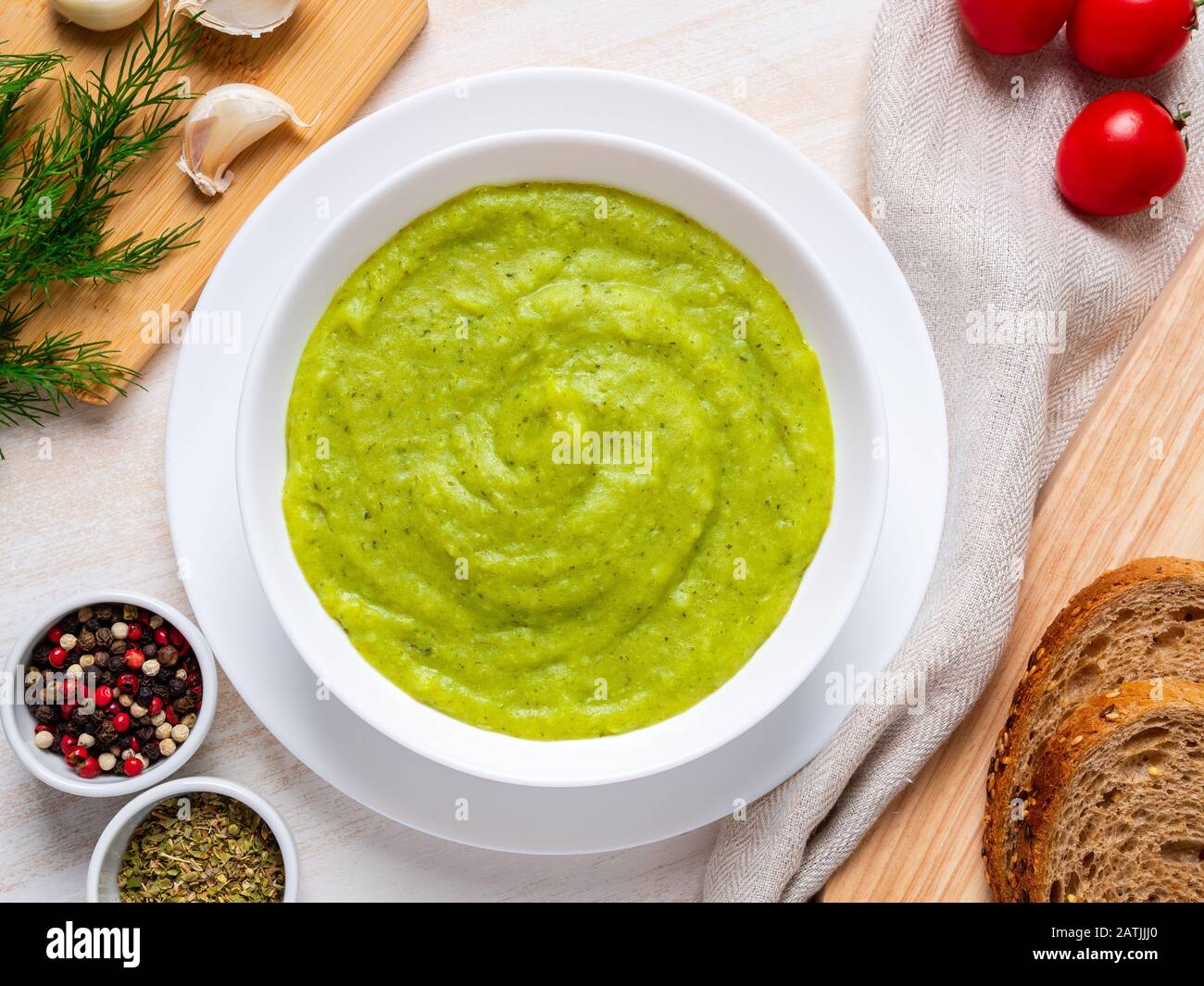 Große weiße Schüssel mit pflanzlich grüner Cremetuppe aus Brokkoli, Zucchini, grünen Erbsen auf weißem Hintergrund, Draufsicht Stockfoto